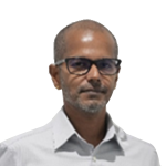 Portrait of a middle-aged man with short hair and glasses, wearing a light gray shirt, looking at the camera.